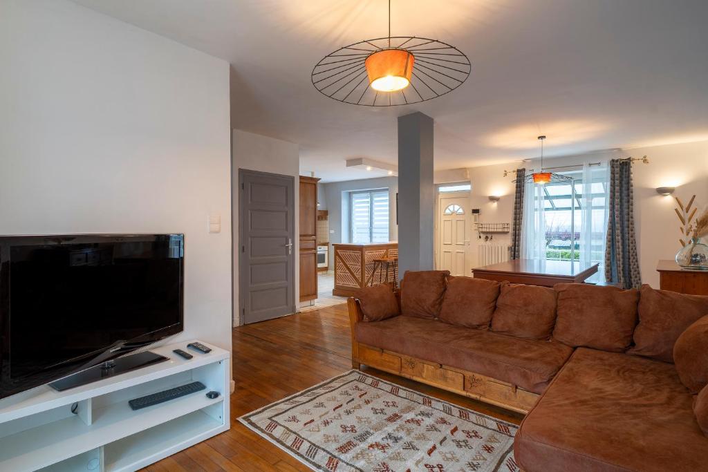 een woonkamer met een bank en een flatscreen-tv bij Gaillarde - Maison pour 8 avec grand jardin in Brive-la-Gaillarde