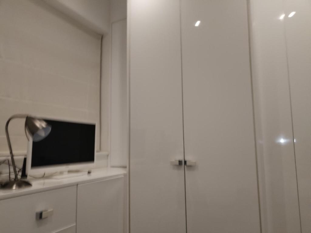 a room with white cabinets and a television on a shelf at single room available in Harpenden