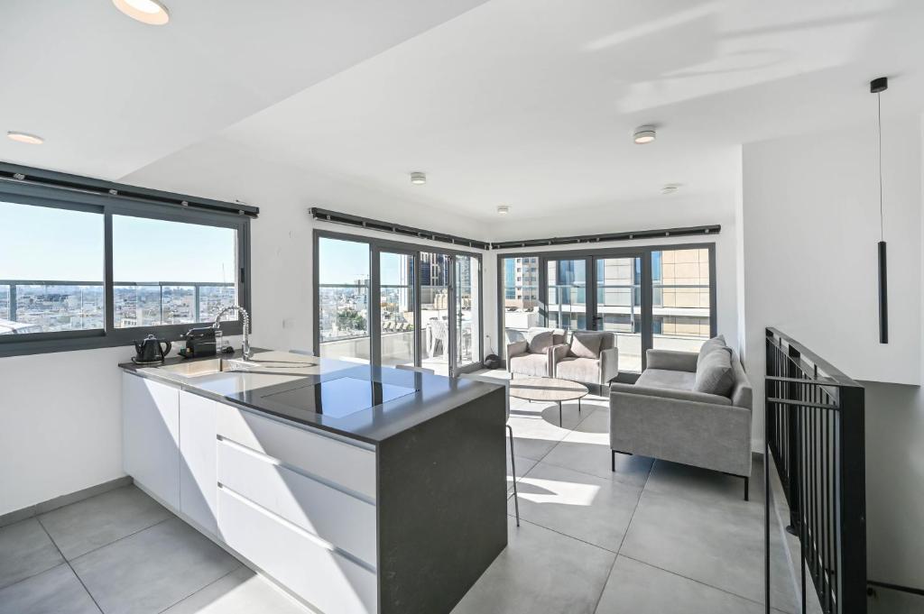 una cucina con bancone e un soggiorno con finestre di Glamorous 3BR Penthouse near Rothschild Boulevard a Tel Aviv