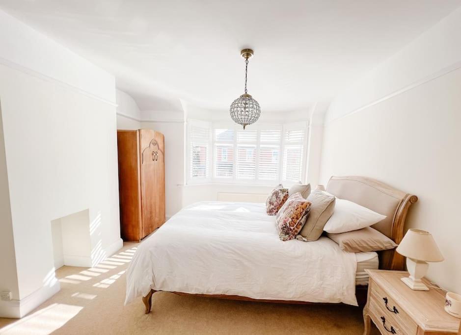 Home in Hereford في هيريفورد: غرفة نوم بيضاء بها سرير و قلادة خفيفة