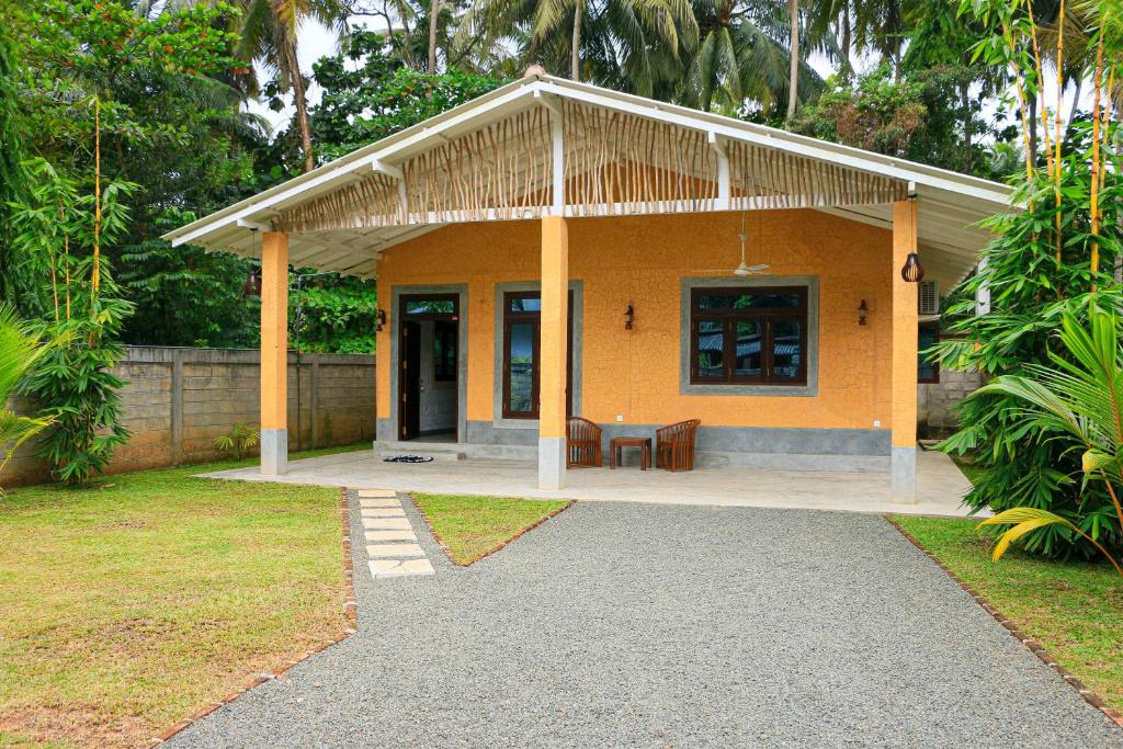 a small yellow house with a table in a yard at Clay House Private Villa in Bentota