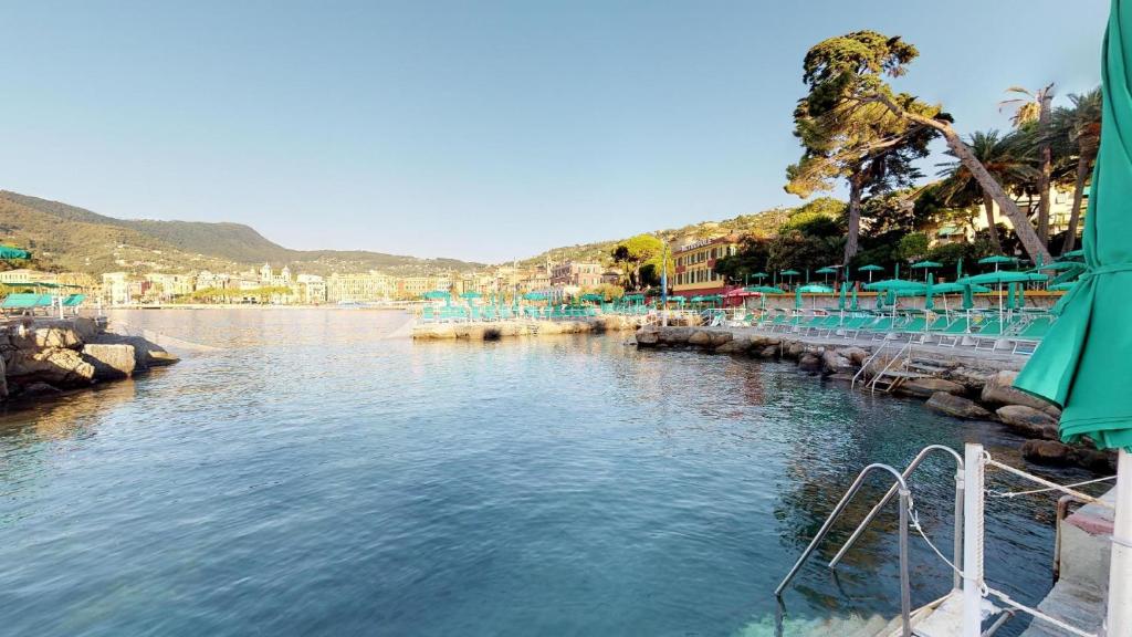 a body of water with blue umbrellas at Hotel Metropole in Santa Margherita Ligure