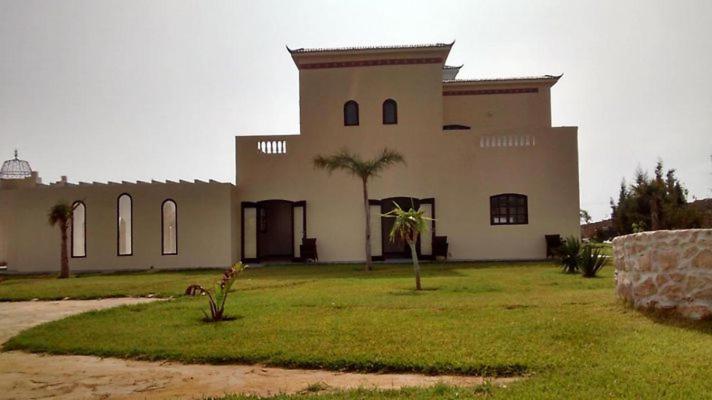 a large building with palm trees in front of it at sidi kaouki ayt karoum in Sidi Kaouki