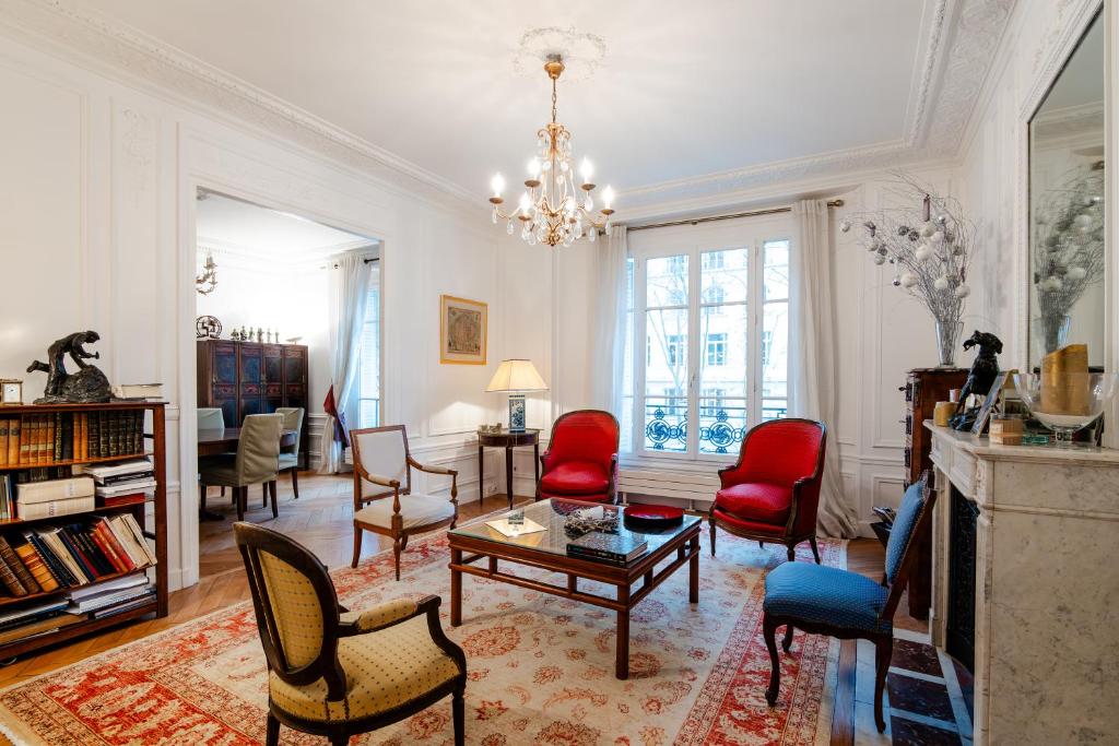 d'un salon avec des chaises rouges et un lustre. dans l'établissement Veeve - Magic of Light, à Paris