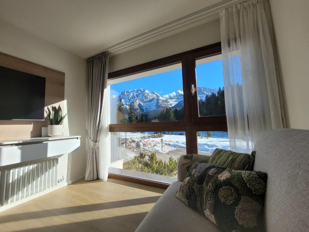 a living room with a large window with a mountain view at SWEET Alps Apartment CCM in Madonna di Campiglio