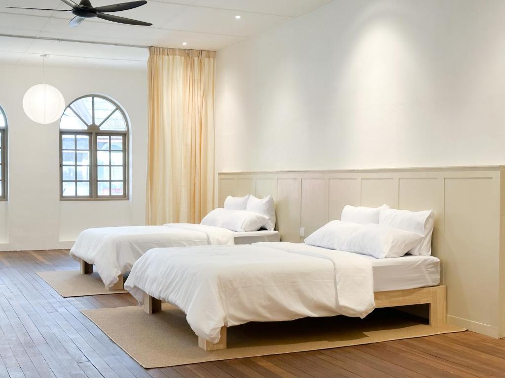 Duas camas num quarto com paredes brancas e um tecto. em Heritage Vacation Inn old street view em Kuching