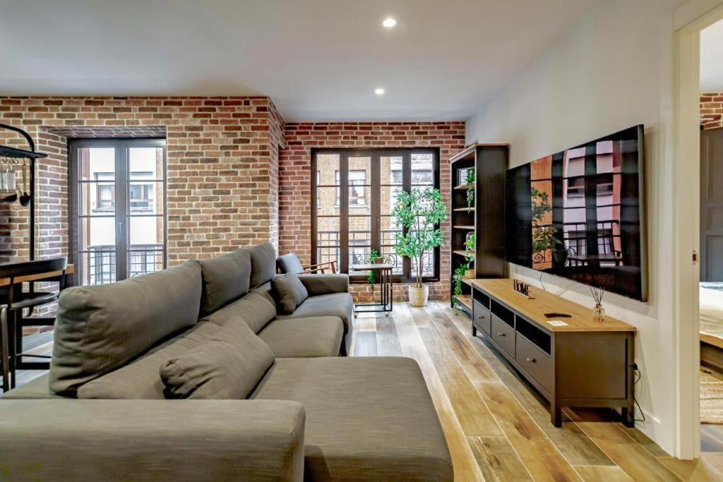 a living room with a couch and a brick wall at Apartamentos JAP Begoña in Gijón