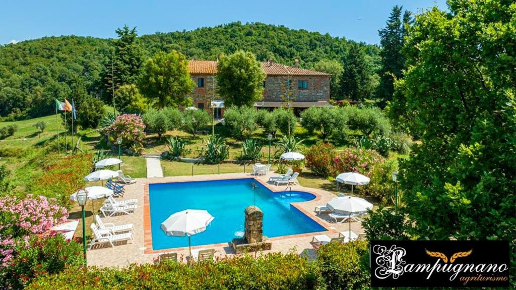 ein Pool mit Sonnenschirmen und Stühlen sowie ein Haus in der Unterkunft Lampugnanino in Civitella Marittima