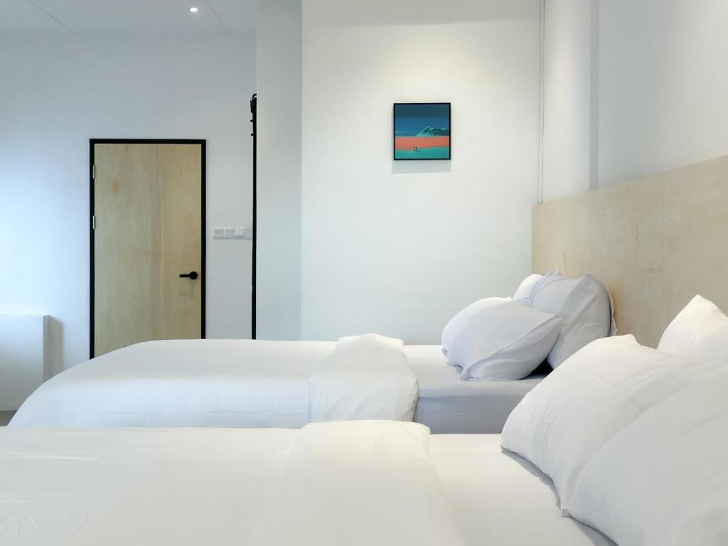 um quarto com duas camas com lençóis brancos e uma porta em Heritage Vacation Inn Balcony em Kuching