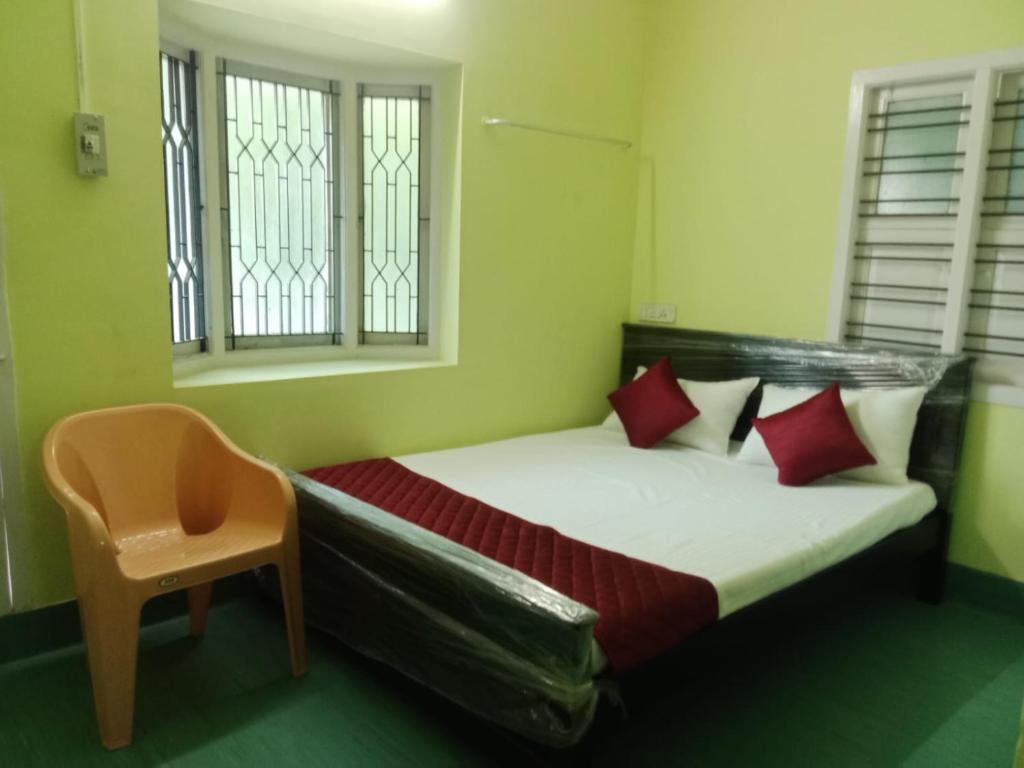 een slaapkamer met een bed met rode kussens en een stoel bij gplushomestay in Madurai