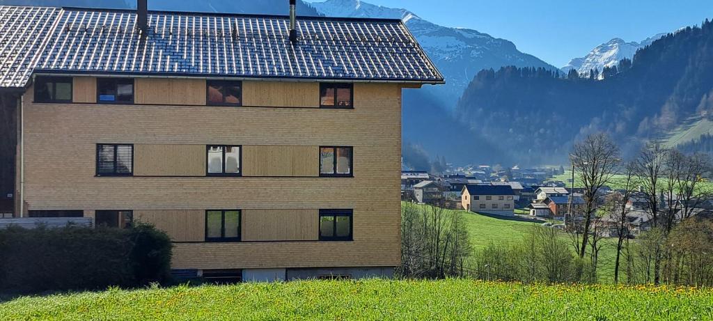 ein Gebäude auf einem Hügel mit einem Berg im Hintergrund in der Unterkunft Ferienwohnung BergTraum in Schoppernau