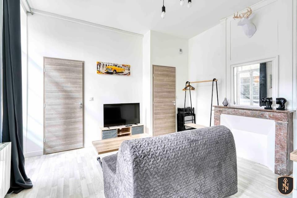 a living room with a couch and a television and a fireplace at La Casa Naia VI — Votre bulle d'air sur la côte in Douvres-la-Délivrande