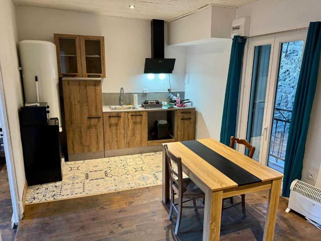 Charmant appartement في Serdinya: مطبخ مع طاولة خشبية وغرفة طعام