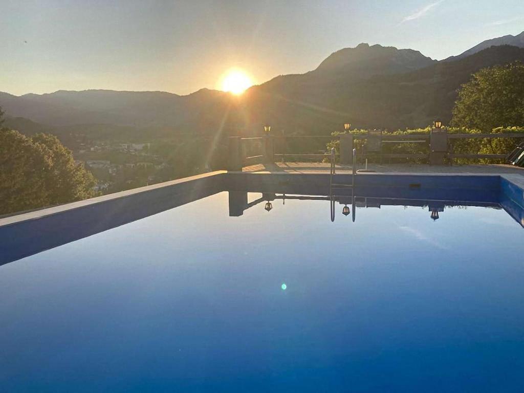 a swimming pool with the sunset in the background at Ferienwohnungen Angerer Kederlehen in Berchtesgaden