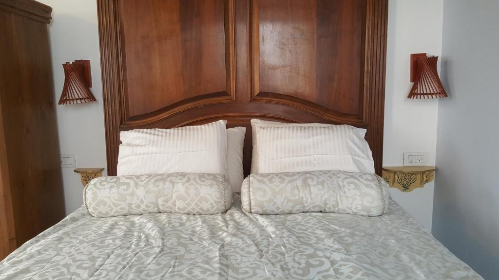 a bed with a wooden head board and two pillows at Jerusalem View in Mevasseret Zion