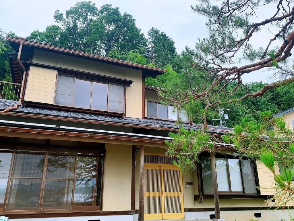 a house with windows and trees in the background at 吉祥莊 in Takayama