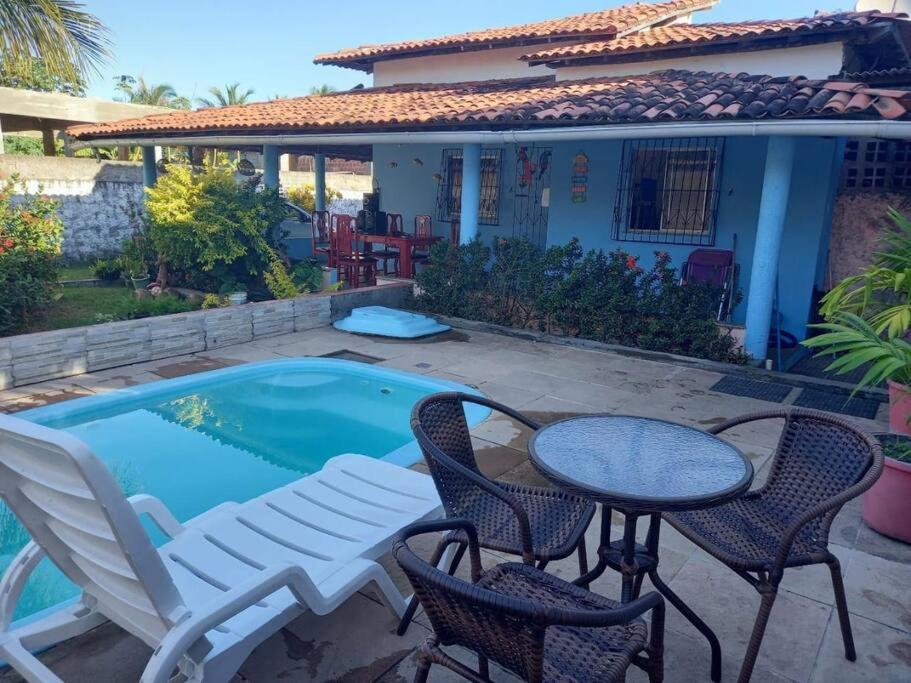 un patio con mesa y sillas junto a una piscina en Casa em berlinque, vera cruz. en Vera Cruz de Itaparica