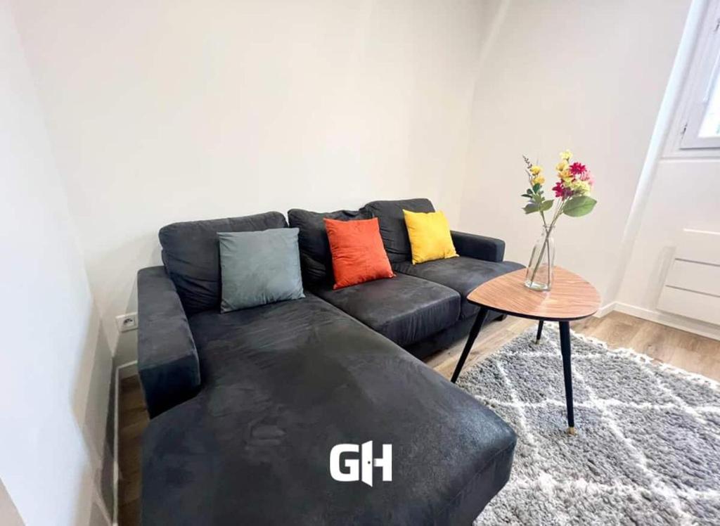 - un canapé noir avec des oreillers colorés dans le salon dans l'établissement L Eclat - Logement moderne proche Paris - Wifi, à Rueil-Malmaison