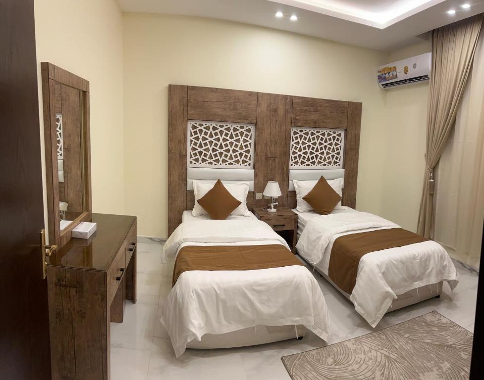 una camera con 2 letti e una testiera in legno di كيان المخيم لشقق الفندقية a Najran