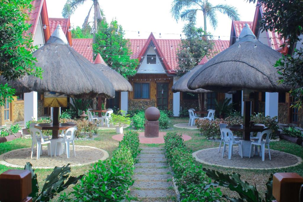 a garden with tables and chairs and umbrellas at Bea's Garden Inn in Puerto Princesa City