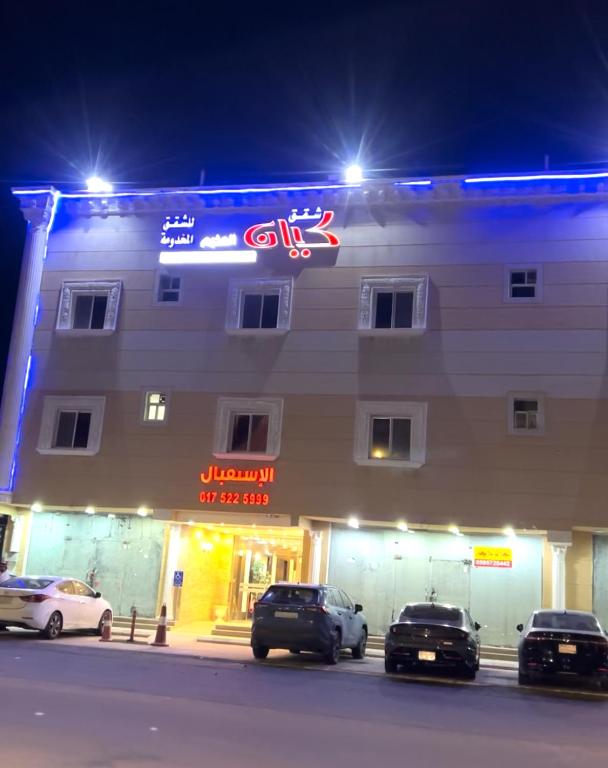 two cars parked in front of a building at night at شقق كيان المخيم للشقق المخدومة in Najran