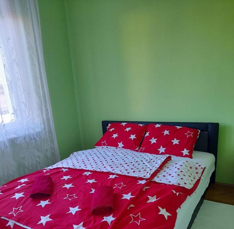 1 cama con edredón rojo y blanco con estrellas blancas en Fehérvadász Vendégház, en Szombathely