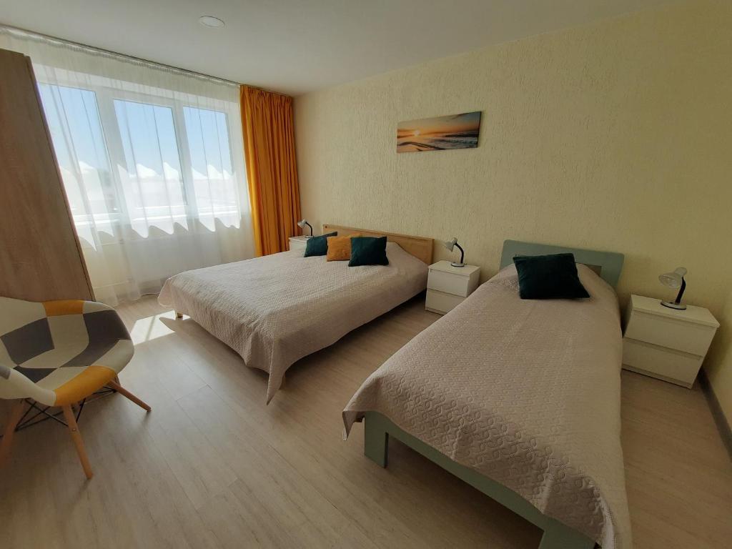 een hotelkamer met 2 bedden en een stoel bij Roze Apartment in Rēzekne