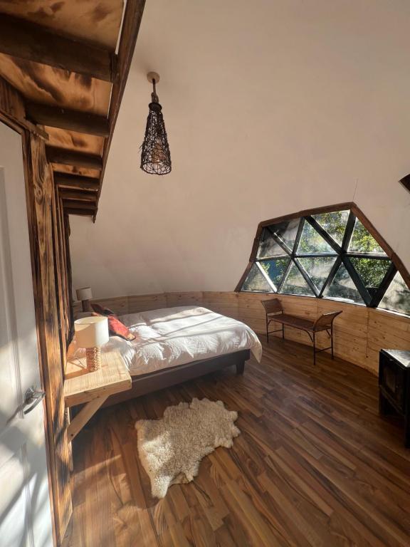 a bedroom with a bed and a large window at Bongalow Hoodoo in Melipeuco