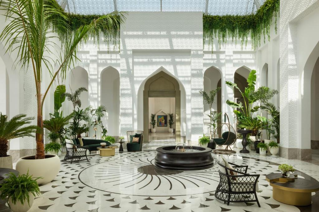 a lobby with a fountain and palm trees and chairs at Raffles Al Areen Palace Bahrain in Manama