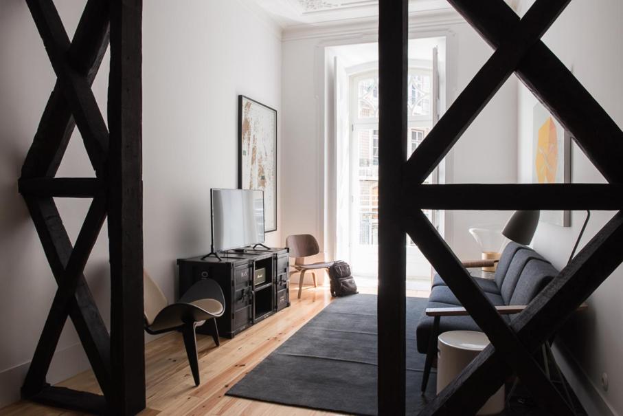 ein Wohnzimmer mit einem Stuhl, einem Sofa und einem TV in der Unterkunft Madalena Orquidea Living Apartments in Lissabon