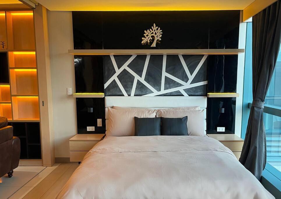 1 dormitorio con 1 cama grande y cabecero blanco y negro en Escape 1BR One Uptown BGC w/ Sound System, en Manila