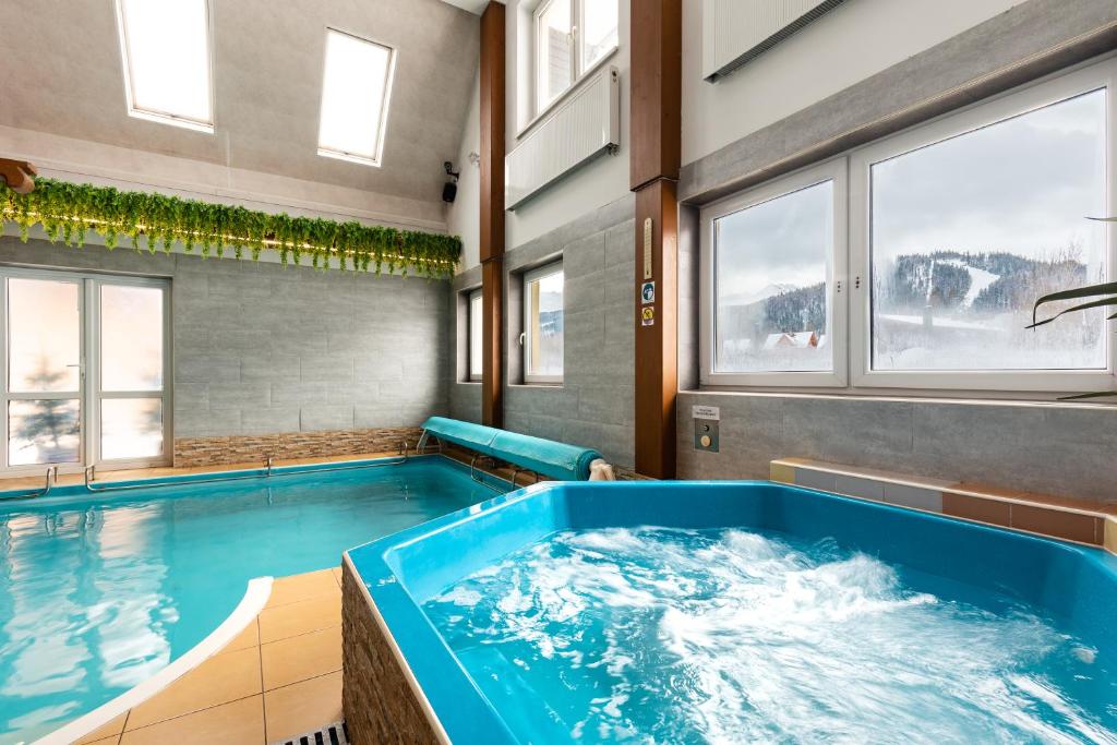 La salle de bains est pourvue d'une grande baignoire bleue et de fenêtres. dans l'établissement Willa Widokowa Wojnar, à Zakopane