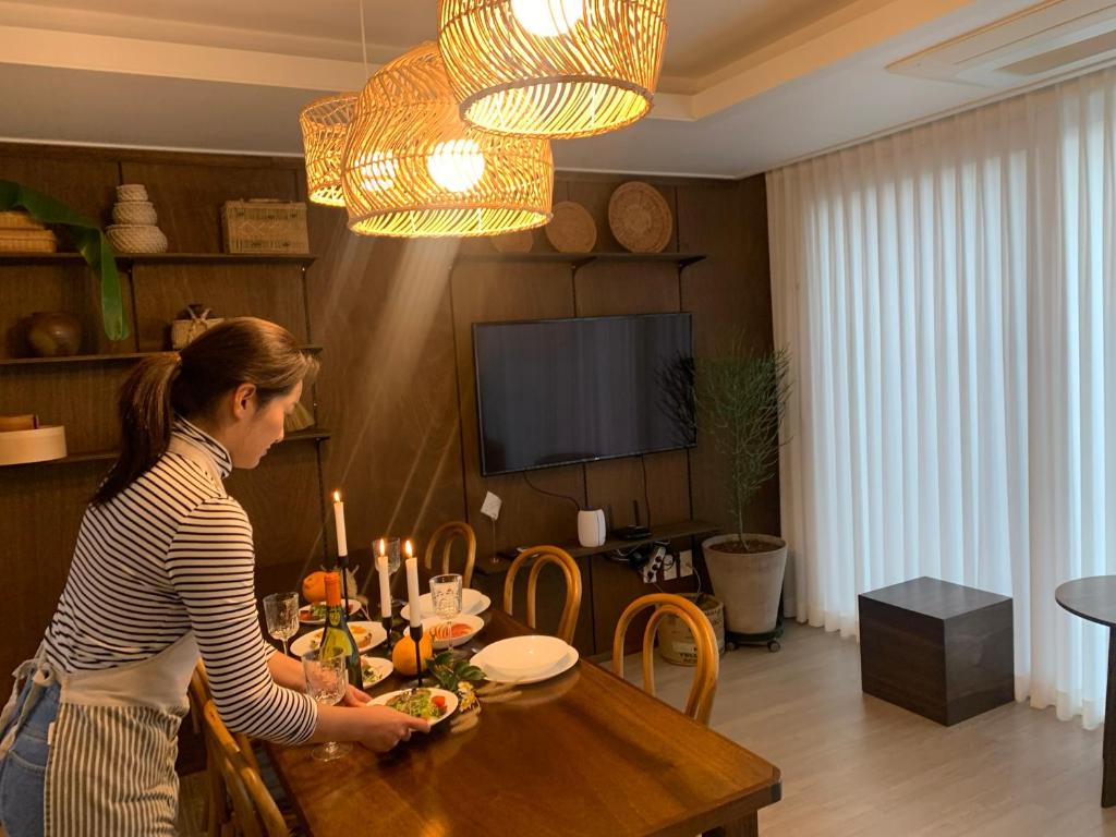 a woman standing at a table in a living room at Misun House in Seogwipo