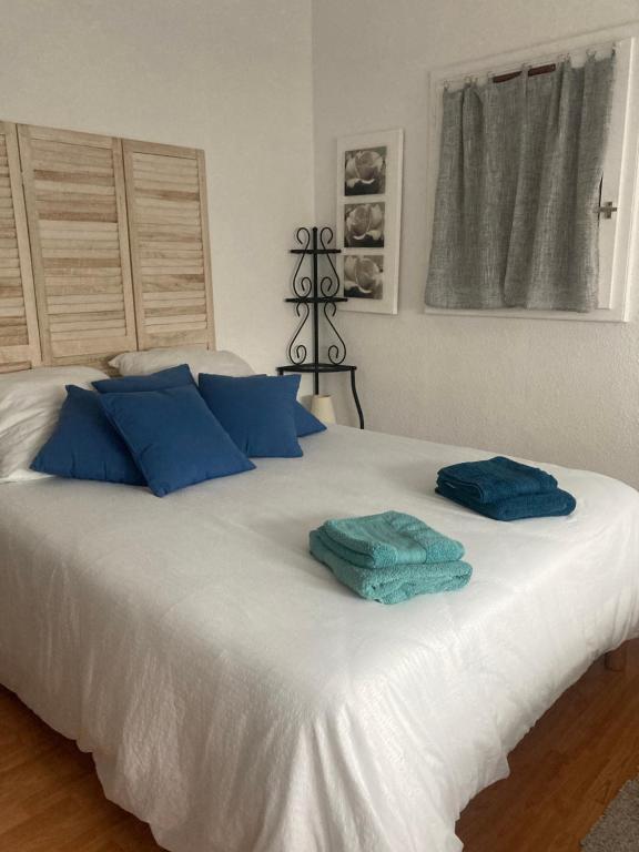 uma grande cama branca com almofadas azuis em Appartement duplex lumineux idéalement situé em Arès