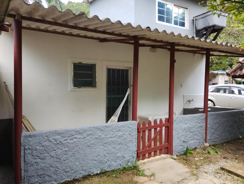 una casa con una puerta roja y una valla en Casinha Pescador en São Sebastião