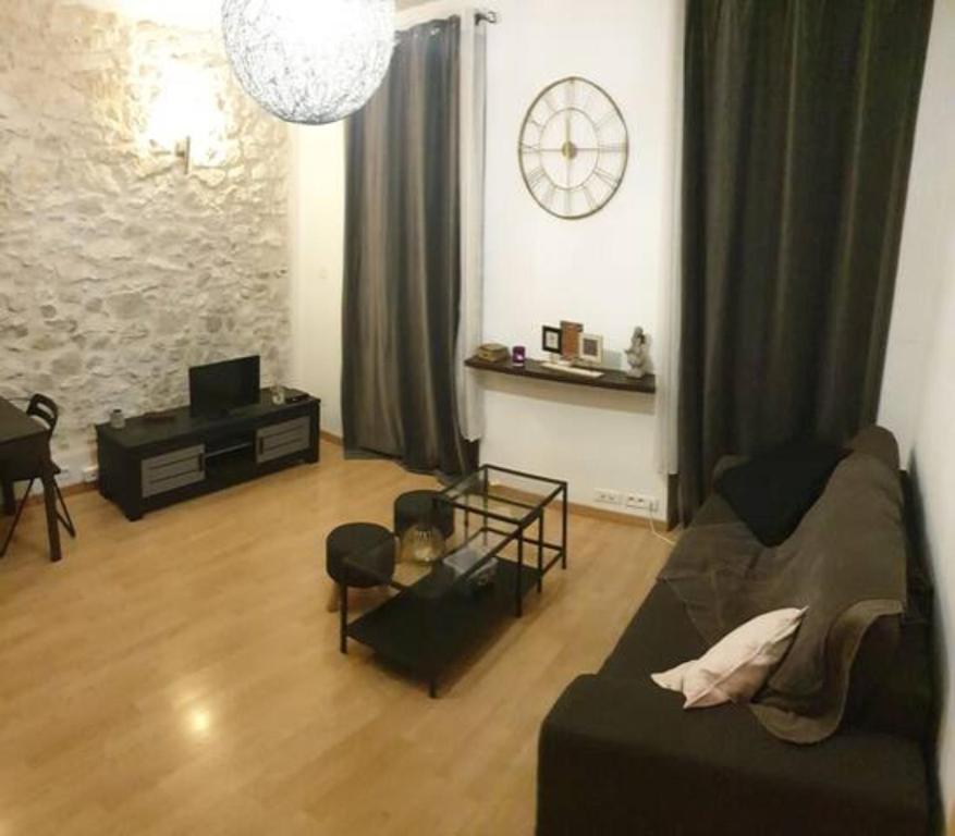 un salon avec un canapé et une horloge au mur dans l'établissement Joli T1+ bien situé dans le 6ème de Marseille, proche commodités, à Marseille