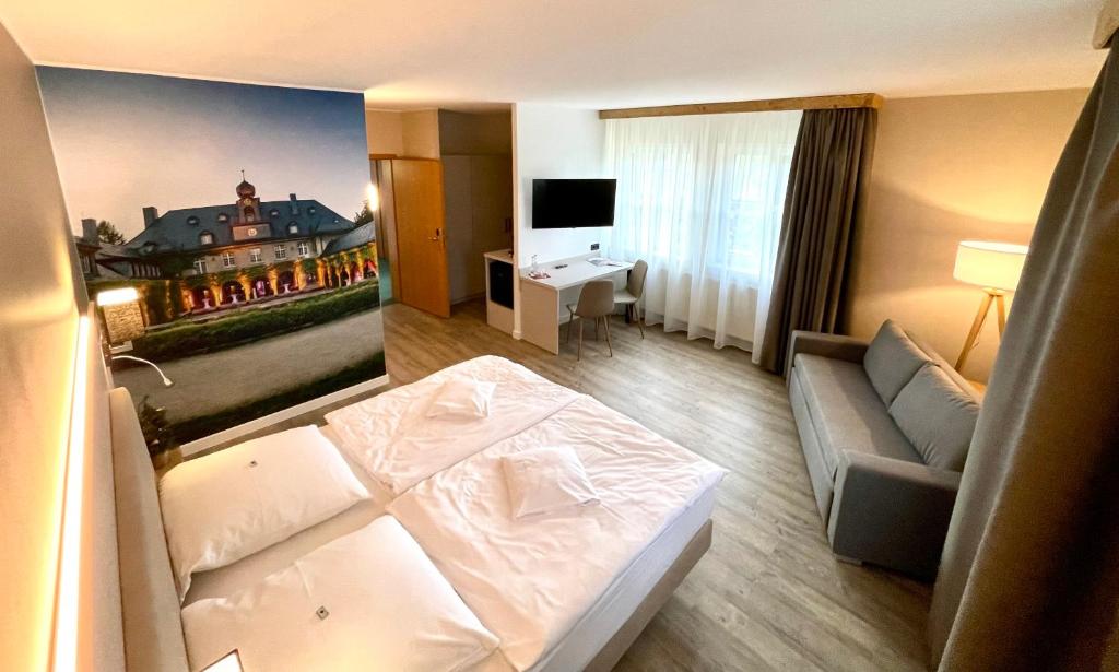a hotel room with a bed and a couch at Hotel &amp; Restaurant Bergfried in Saalfeld