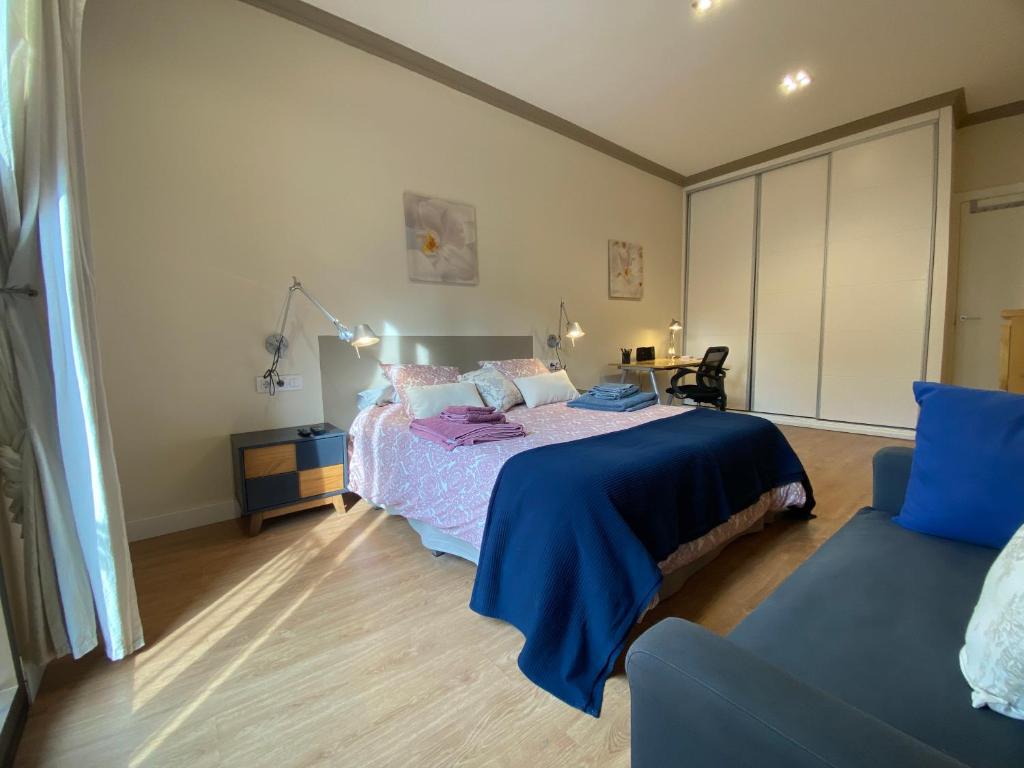 ein Schlafzimmer mit einem Bett mit einer blauen Decke und einer Couch in der Unterkunft Spatious luxe apartment Paseo de Gracia Diagonal in Barcelona