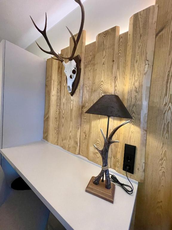 a table with a lamp and a deer head on the wall at Hotel &amp; Restaurant Bergfried in Saalfeld