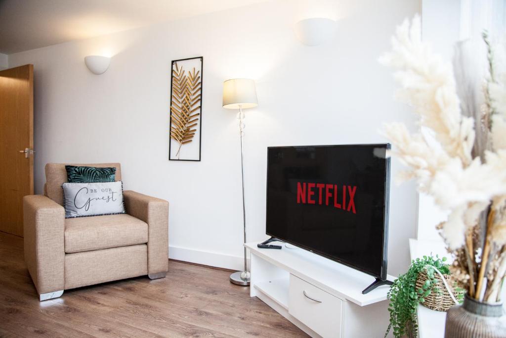 a living room with a flat screen tv and a chair at PENTHOUSE - LIVERPOOL City Centre & Royal Hospital Location in Liverpool