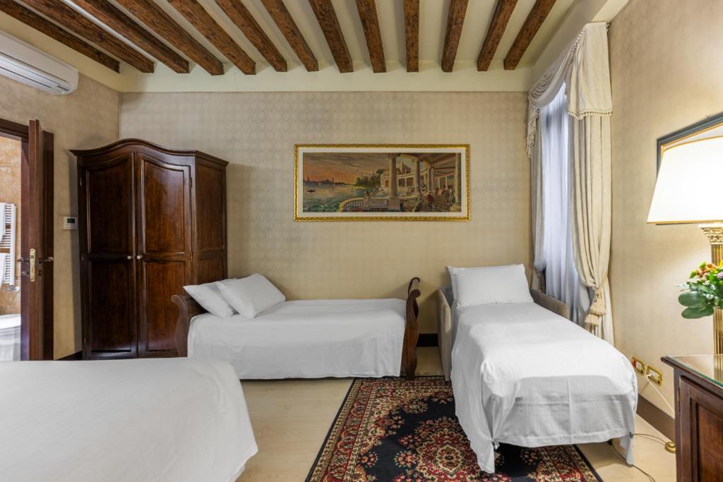 a hotel room with two beds and a table at Ca' Del Nobile in Venice