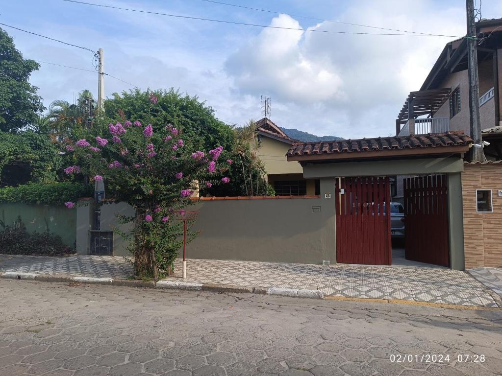 una casa con una puerta y un árbol con flores rosas en Casa prática e completa próxima de tudo en Ubatuba