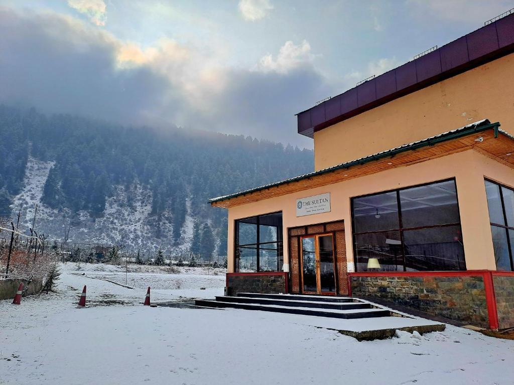 a building with snow on the ground in front of it at The Sultan Resort in Kulan