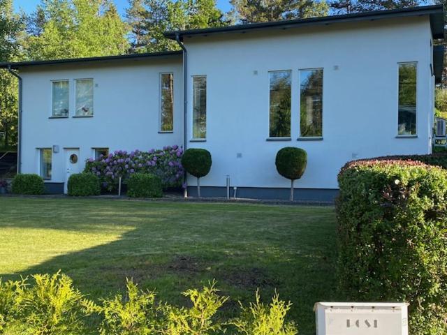 una gran casa blanca con arbustos delante en Kolmården, Generös villa en Kolmården