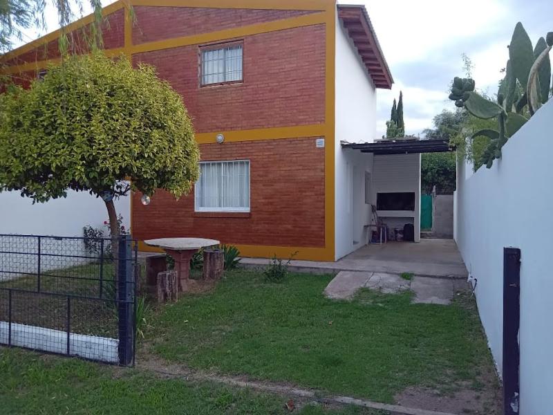 a house with a tree and a table in front of it at Mi Recreo DUPLEX in Villa Cura Brochero