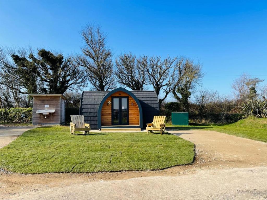 a small cabin with two chairs in front of it at Ashbourne Heights Holiday Park in Ashbourne