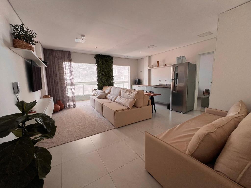 Una sala de estar con un sofá y una cocina. en Unitá Praia Grande Boqueirão, en Praia Grande