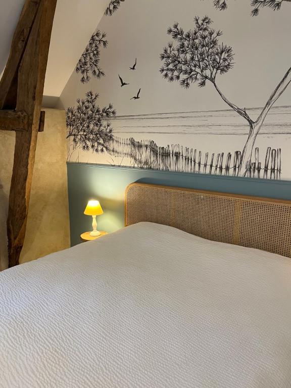 - une chambre avec un lit et un mur orné d'oiseaux dans l'établissement La Chaumière de la Chaize, à Saint-Jouan-des-Guérets