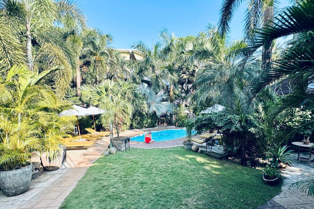 un patio trasero con piscina y palmeras en Casa Da Praia, en Candolim