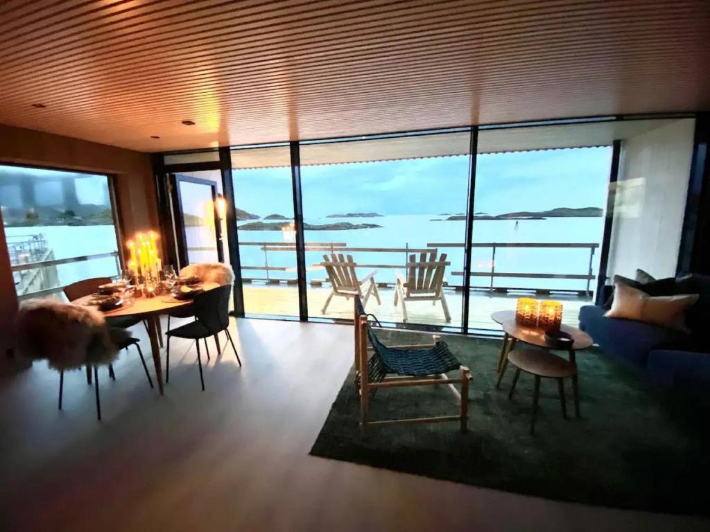 a living room with a table and chairs and a view of the ocean at Waterfront apartment with panoramic sea view in Henningsvær